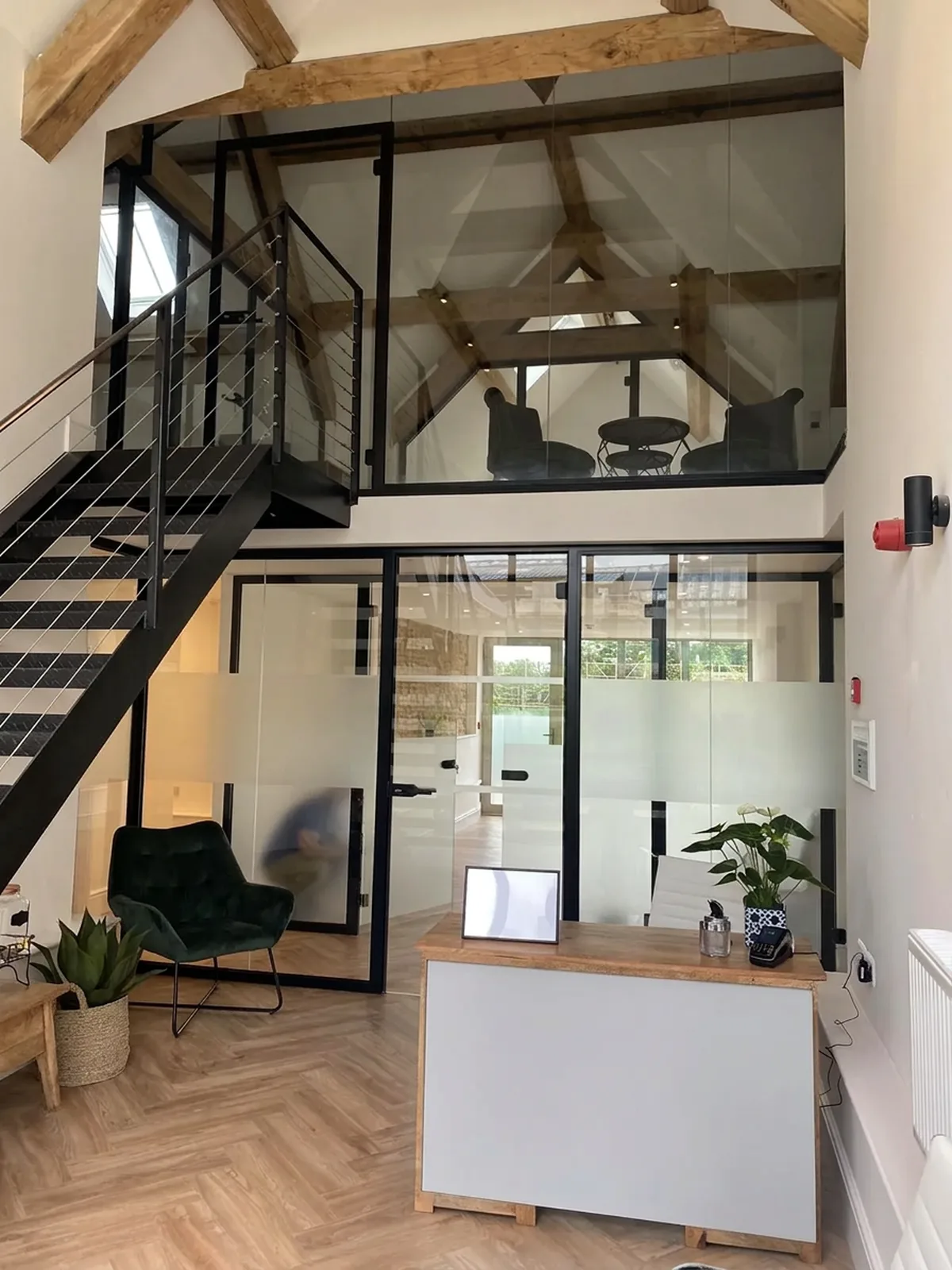 Black-framed glazed partitions in a modern reception area with a mezzanine above